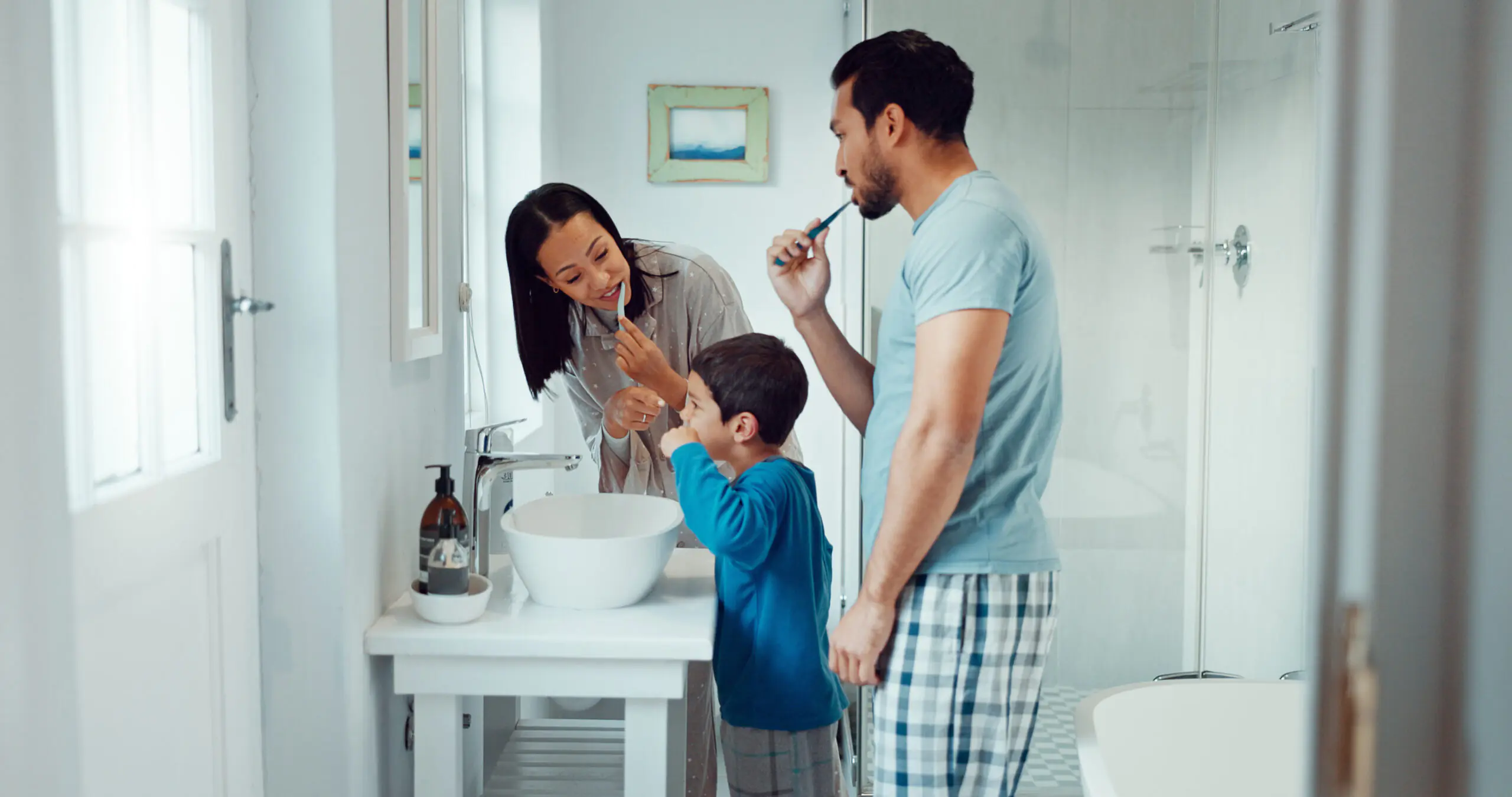 Family brushing their teeth together at a bathroom sink